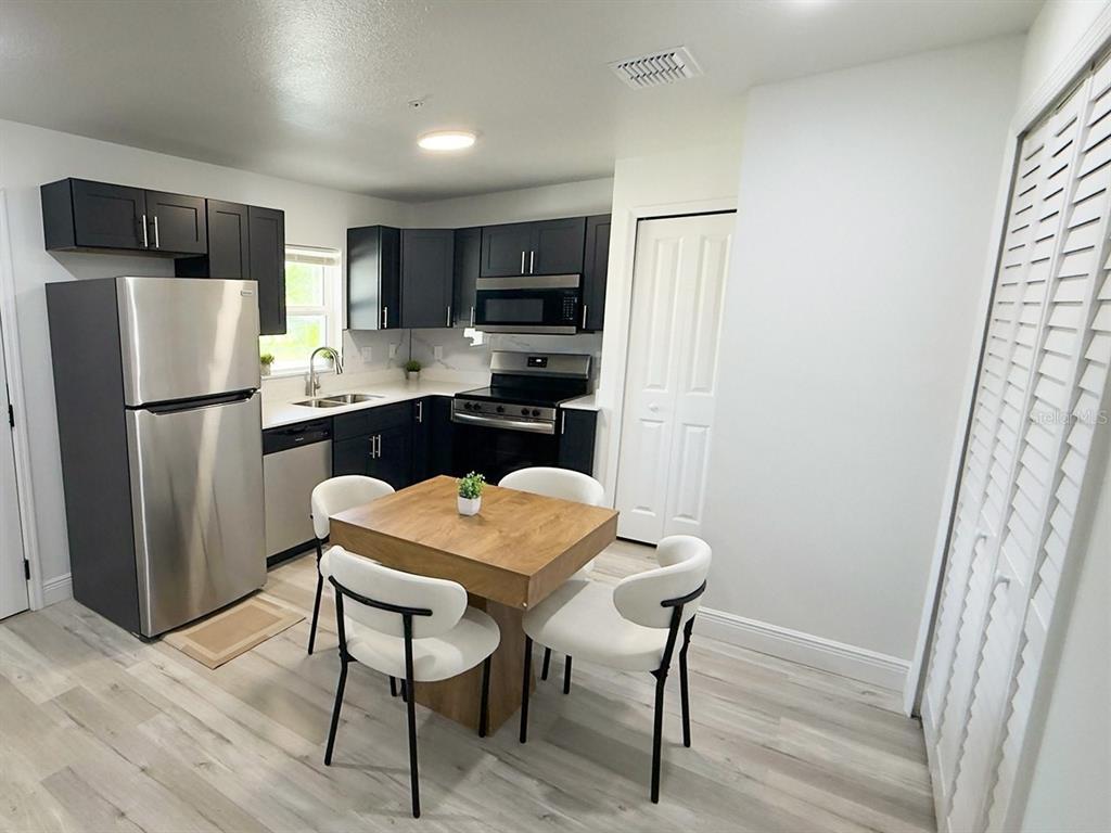 A kitchen features dark cabinets, stainless steel appliances, and a small dining table with chairs — 2201 CONWAY DRIVE UNIT 201, DELTONA, FL