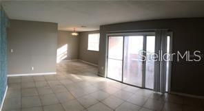 An open-concept living area features light-colored tile flooring, grey walls, and a sliding glass door — 3984 VERSAILLES DRIVE UNIT 3984C, ORLANDO, FL