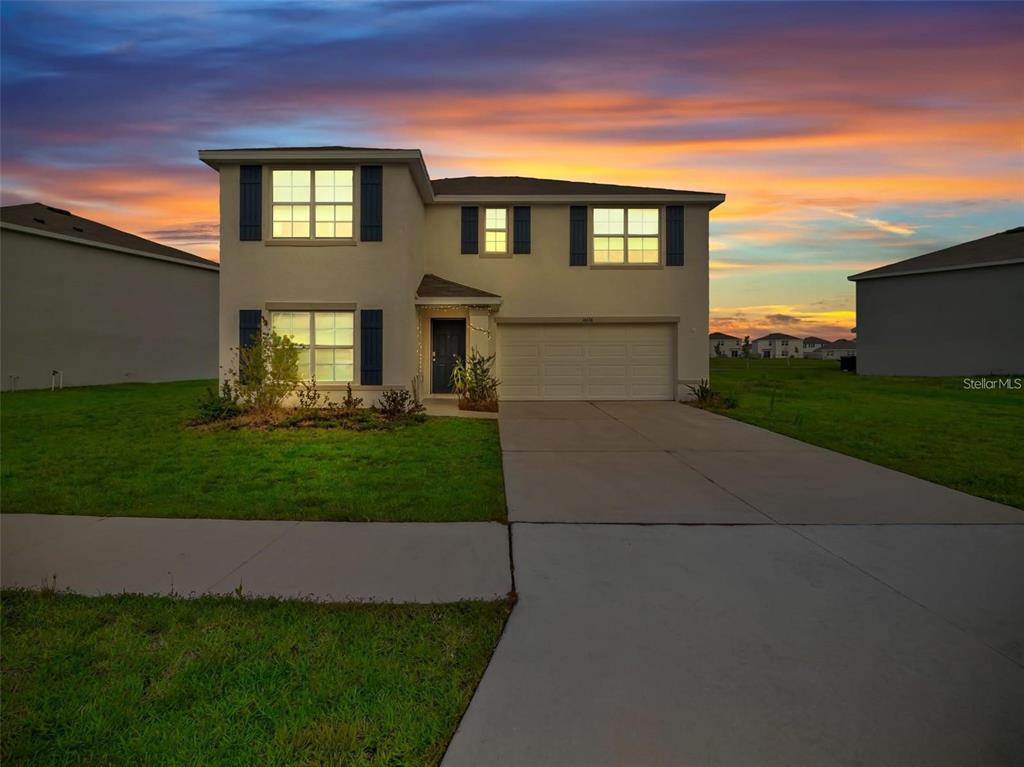 A two-story suburban house with a concrete driveway, stucco exterior, and blue window shutters — 16636 WINDMILL FORGE PASS, WIMAUMA, FL