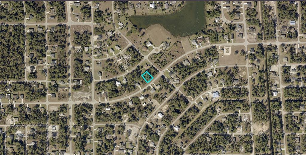 An aerial view of a residential neighborhood with a vacant lot highlighted in blue — 845 SUNRISE BOULEVARD, LEHIGH ACRES, FL