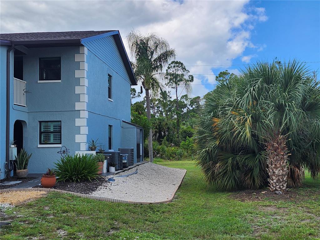 A blue two-story building exterior features a gravel landscape bed and a large palm tree — 87 BOUNDARY BOULEVARD UNIT 7, ROTONDA WEST, FL