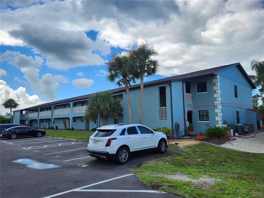 A blue two-story apartment building with a parking lot and a circled ground-floor unit — 87 BOUNDARY BOULEVARD UNIT 7, ROTONDA WEST, FL