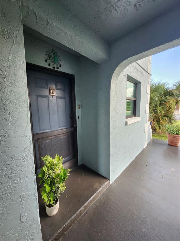 A light blue exterior wall features a dark blue front door with a screen door — 87 BOUNDARY BOULEVARD UNIT 7, ROTONDA WEST, FL