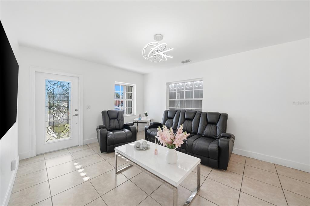 A living room features white walls, tile flooring, a black sofa, and a matching recliner — 465 E 38TH STREET, HIALEAH, FL