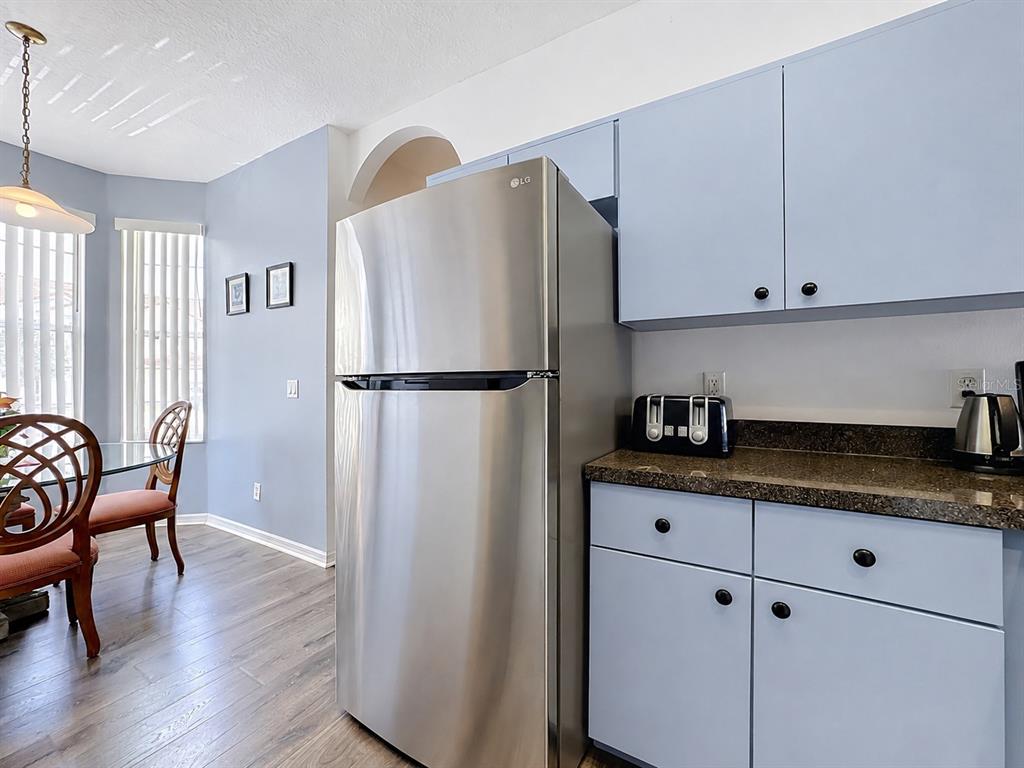 A kitchen features wood cabinets, dark granite countertops, white appliances, and a double-basin sink — 1201 S BEACH CIR, KISSIMMEE, FL