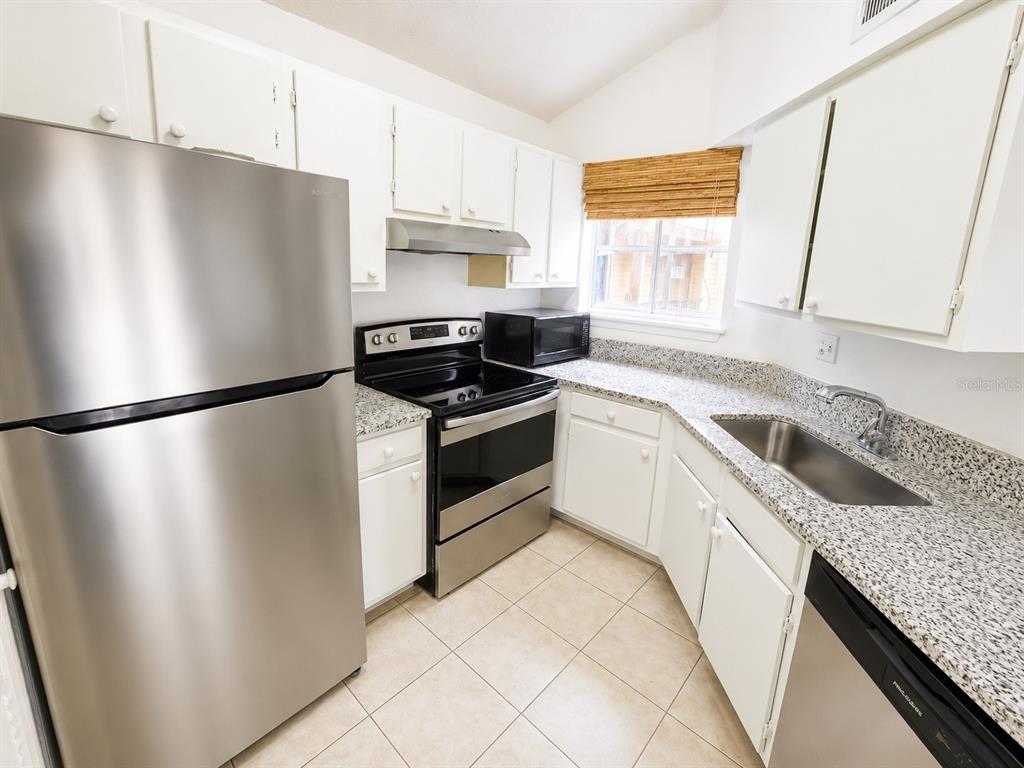 A kitchen features stainless steel appliances, white cabinets, and granite countertops — 1908 LAKE ATRIUMS CIRCLE UNIT 0, ORLANDO, FL