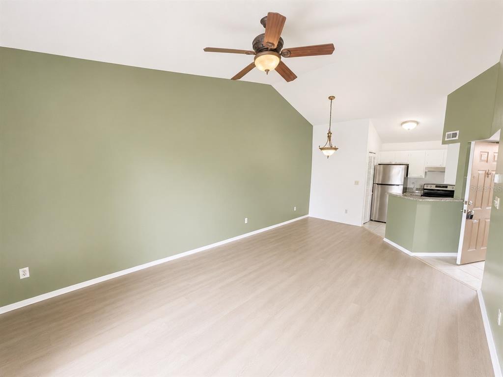 An empty living room with light wood-look flooring, a green accent wall, and ceiling fan — 1908 LAKE ATRIUMS CIRCLE UNIT 0, ORLANDO, FL