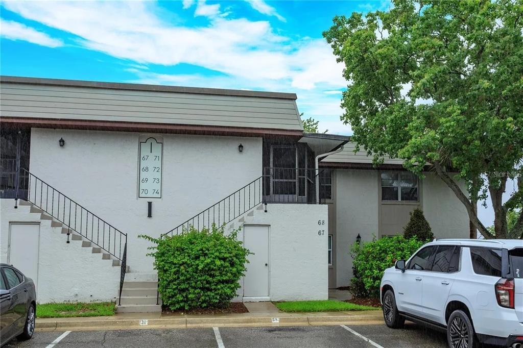 A two-story apartment building exterior with a staircase leading to the second floor — 68 WINDTREE LANE UNIT 201, WINTER GARDEN, FL
