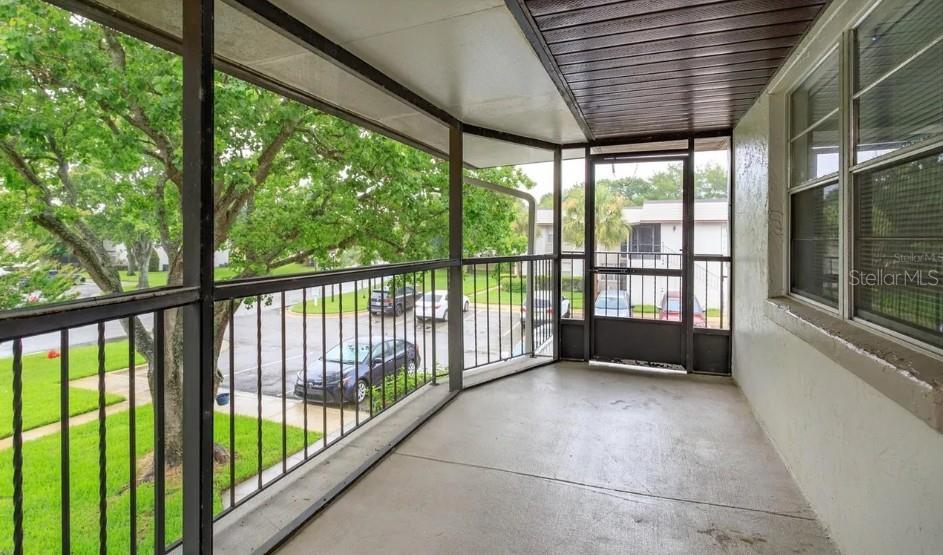 A covered balcony with a concrete floor, metal railings, and a screen door — 68 WINDTREE LANE UNIT 201, WINTER GARDEN, FL