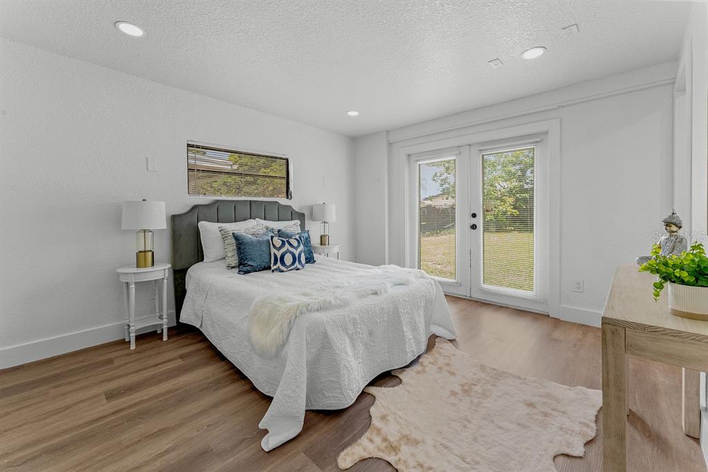 A living room with light wood floors, two armchairs, a sofa, and an open kitchen — 849 LOGAN DRIVE, LONGWOOD, FL