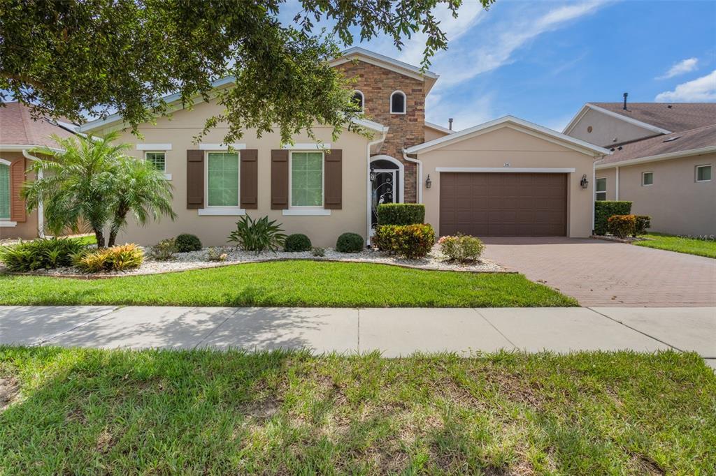 A tan single-story house with a stone facade, brown shutters, and a two-car garage — 290 SILVER MAPLE ROAD, GROVELAND, FL