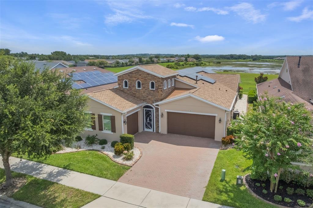 An aerial view of a single-story suburban house with a stone-accented tower and solar panels — 290 SILVER MAPLE ROAD, GROVELAND, FL