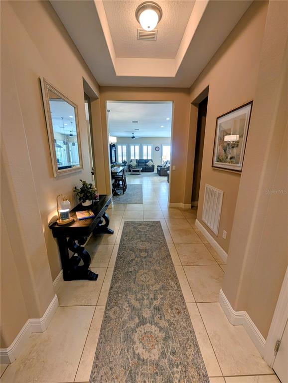 A tiled hallway with a runner rug leads to an open-concept living area — 290 SILVER MAPLE ROAD, GROVELAND, FL