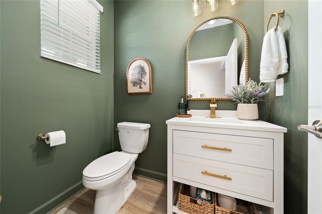 A half bathroom features dark green walls, a white vanity, and a gold-framed arched mirror — 3040 PARK VALE ROAD, ST CLOUD, FL