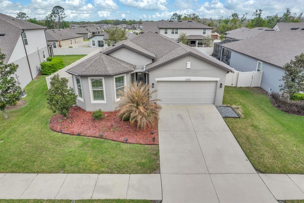An exterior view of a single-story suburban house with a gray facade and concrete driveway — 12653 PALAPA LOOP, SPRING HILL, FL