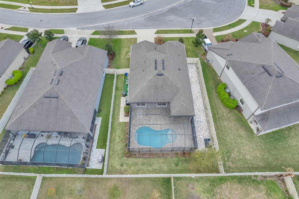 An aerial view shows three suburban houses with swimming pools and fenced backyards — 12653 PALAPA LOOP, SPRING HILL, FL