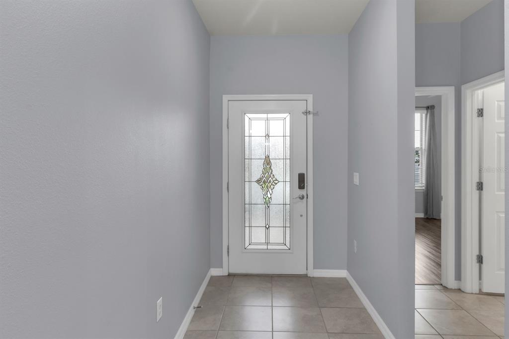An entryway features light gray walls, tile flooring, and a white door with decorative glass — 12653 PALAPA LOOP, SPRING HILL, FL