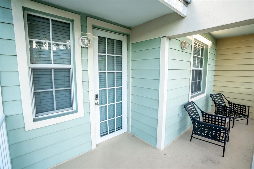 A covered patio features light green siding, a glass-paneled door, and two black metal chairs — 465 BAHIA BEACH BOULEVARD, RUSKIN, FL