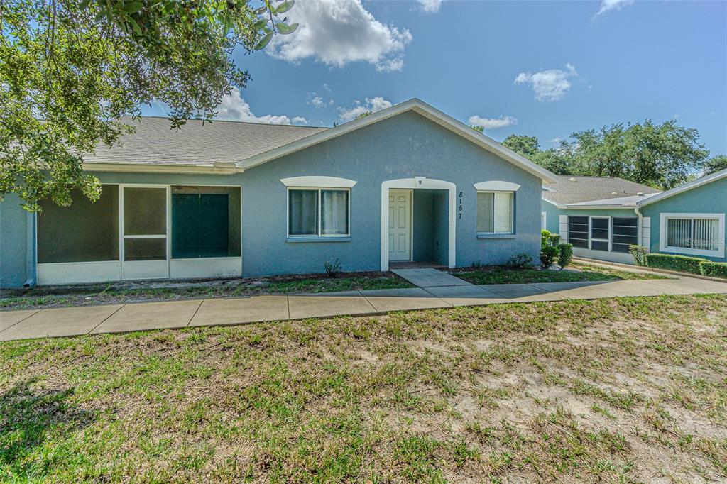 A blue single-story house with a screened-in porch and a concrete walkway in front — 8157 STURBRIDGE COURT, WEEKI WACHEE, FL