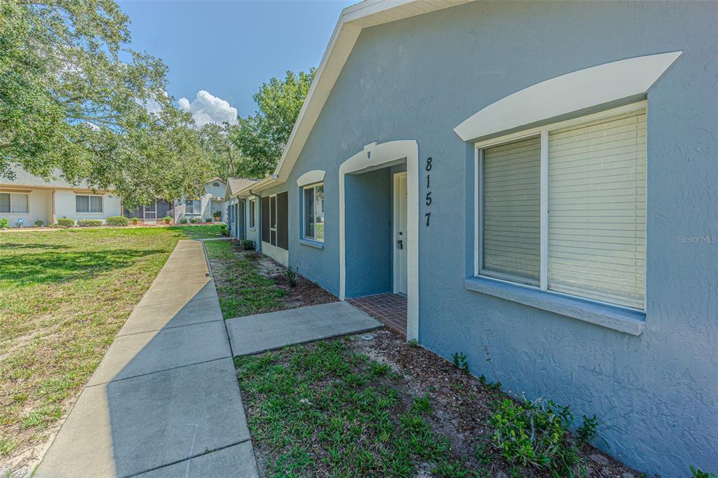 A blue exterior wall of a single-story home features a front entrance and a window — 8157 STURBRIDGE COURT, WEEKI WACHEE, FL