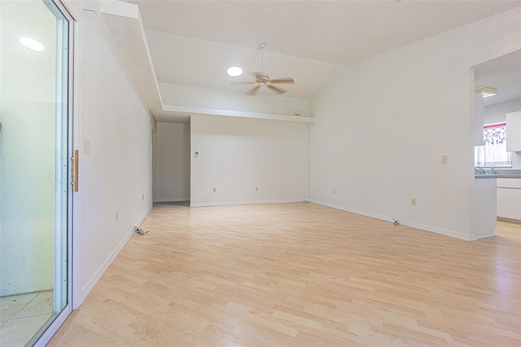 An empty living room features light wood-look flooring, white walls, and a ceiling fan — 8157 STURBRIDGE COURT, WEEKI WACHEE, FL