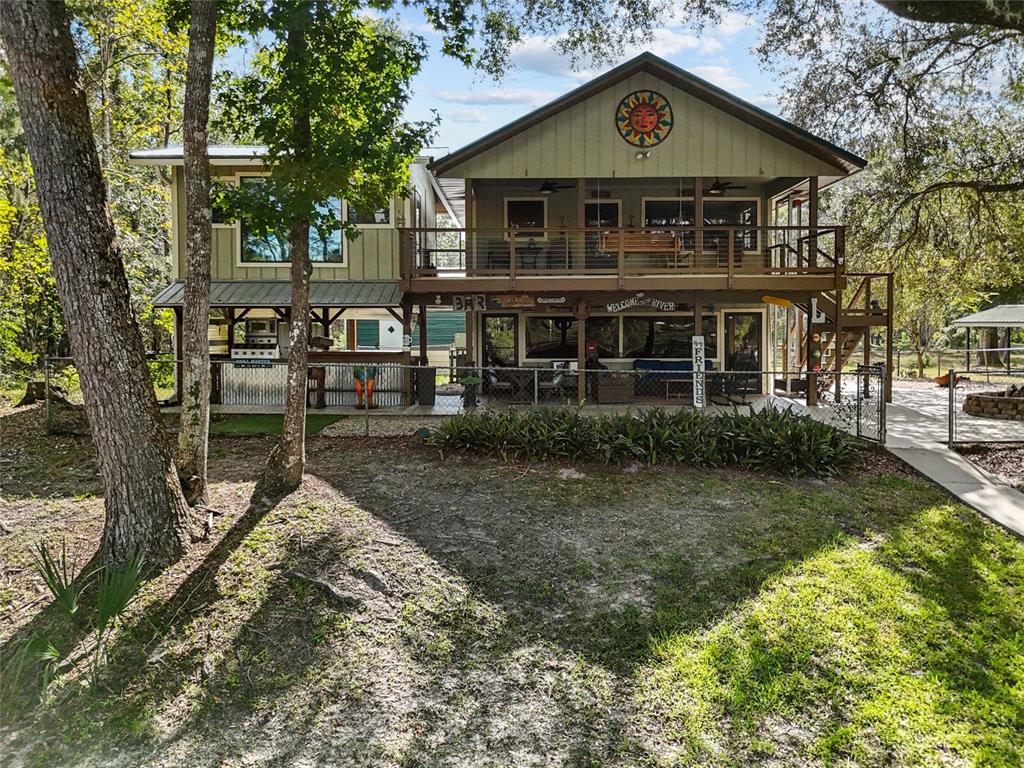 A two-story house with a large wooden deck, a ground-level bar, and a sun decoration — 1069 SE SUWANNEE TRAIL, BRANFORD, FL