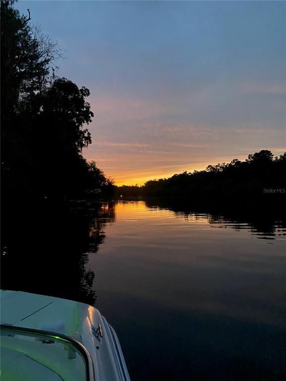 A view from a boat on a calm river at sunset with silhouetted trees — 1069 SE SUWANNEE TRAIL, BRANFORD, FL