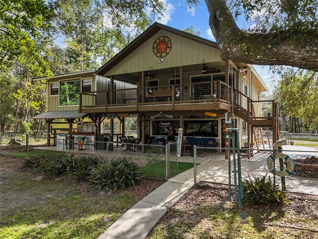 A two-story house with a large wooden deck, ground-level patio, and a sun wall decoration — 1069 SE SUWANNEE TRAIL, BRANFORD, FL
