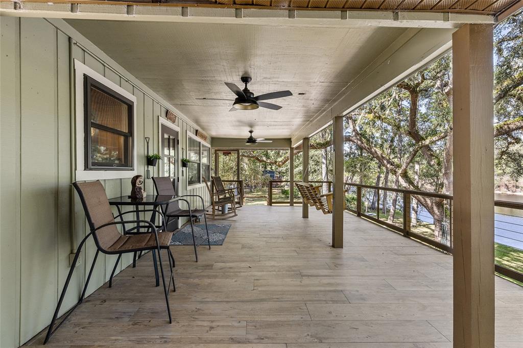 A covered wooden deck features outdoor furniture, ceiling fans, and a view of the water — 1069 SE SUWANNEE TRAIL, BRANFORD, FL