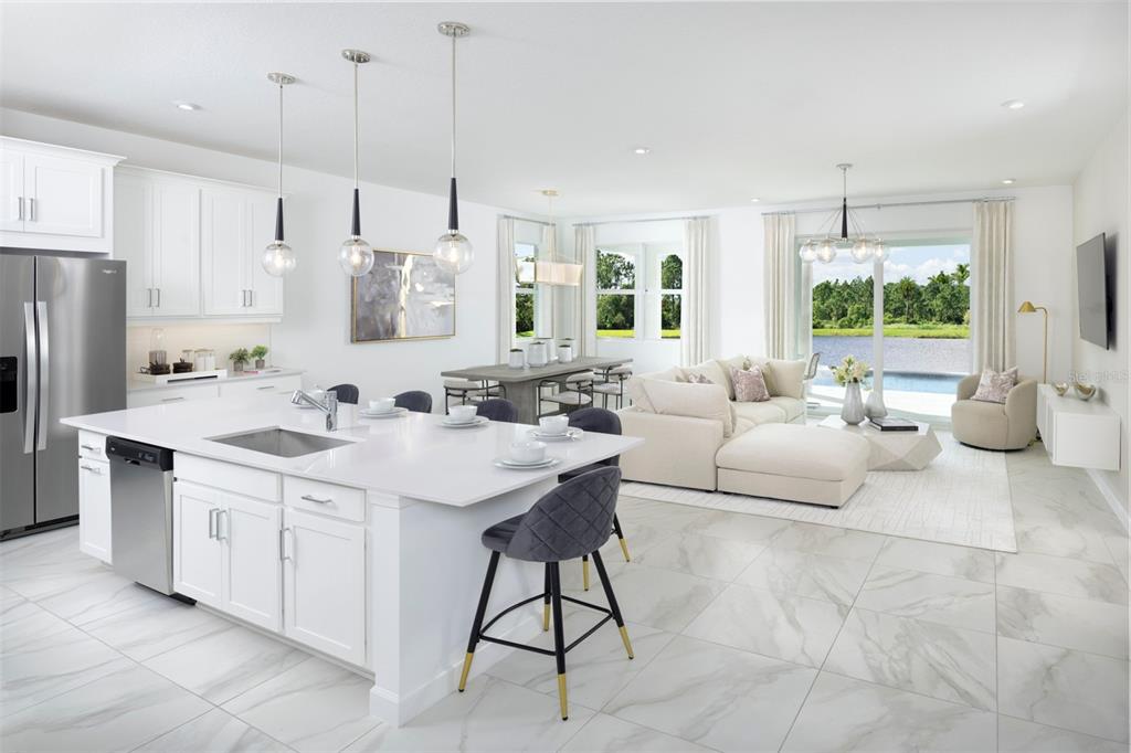 A modern open-concept kitchen and living area featuring white cabinetry, a large island, and lake views — 18501 VISTA PARK, VENICE, FL