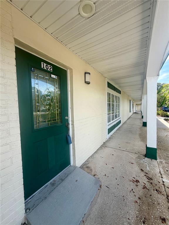 An office space features a wooden L-shaped desk, two computer monitors, and an exit door — 28960 US HIGHWAY 19 N UNIT 102, CLEARWATER, FL