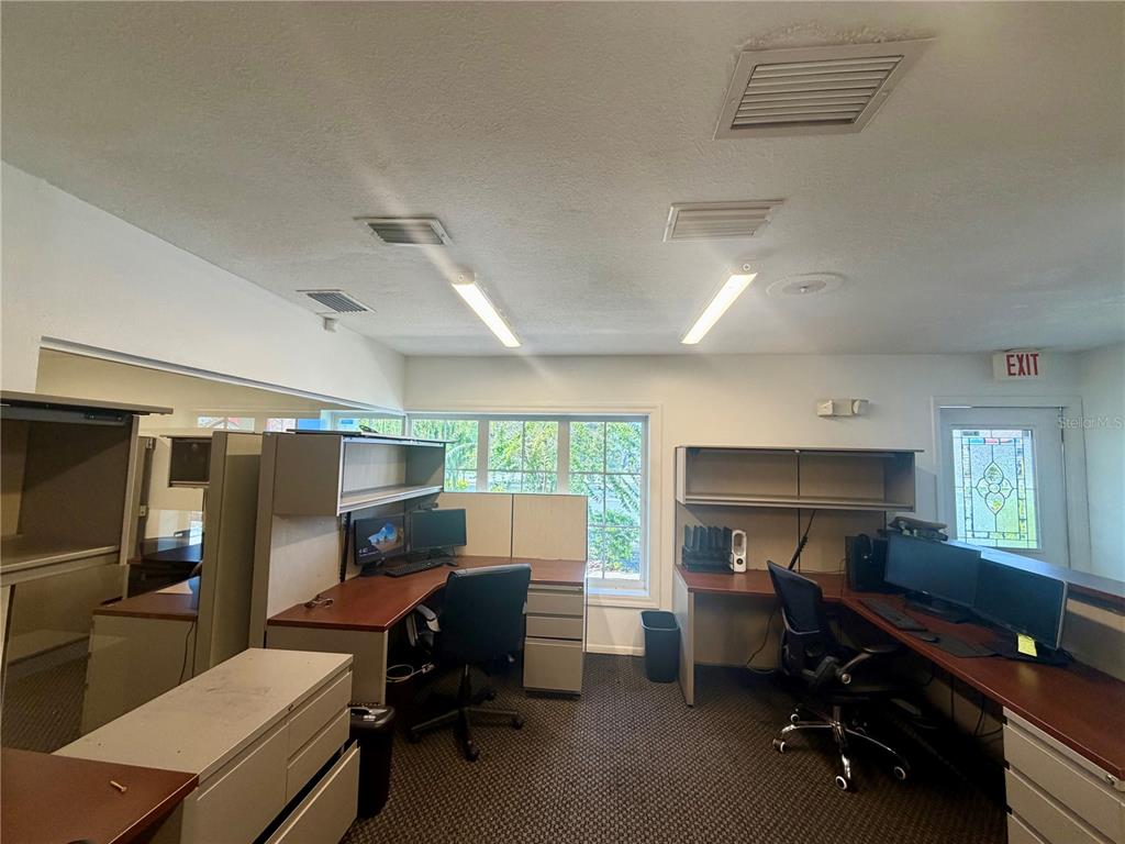 An office space features three modular desks with chairs, computers, and large windows — 28960 US HIGHWAY 19 N UNIT 102, CLEARWATER, FL