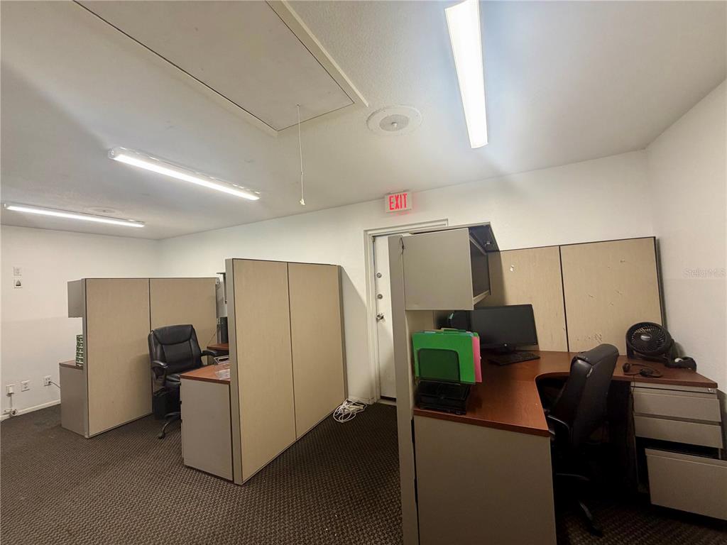 A home office features two desks, multiple computer monitors, office chairs, and stacked storage boxes — 28960 US HIGHWAY 19 N UNIT 102, CLEARWATER, FL