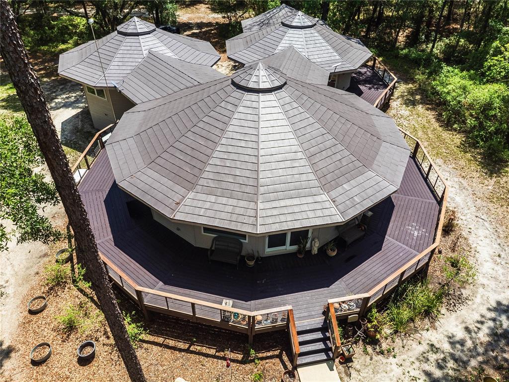 A round house with a wrap-around wooden deck sits in a wooded area — 13797 NE 199TH STREET, WALDO, FL