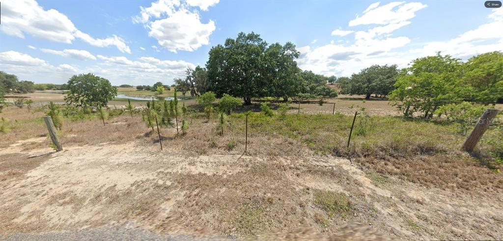 A grassy, undeveloped lot features scattered trees, a small pond, and a wire fence — LIBBY ROAD, BABSON PARK, FL