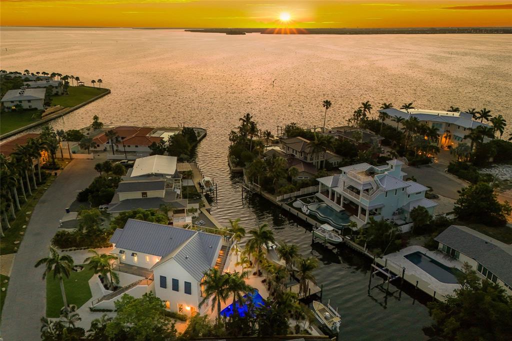 An aerial view shows waterfront homes with pools and boat docks along a canal at sunset — 511 59TH STREET, BRADENTON BEACH, FL