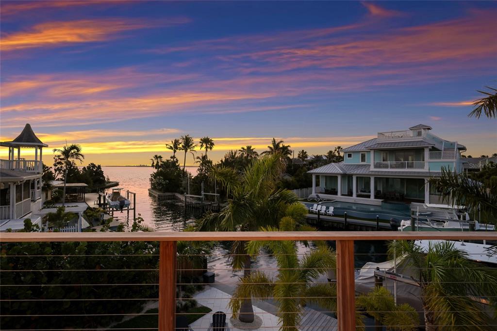 An elevated view of a waterfront home with a pool, boat dock, and sunset sky — 511 59TH STREET, BRADENTON BEACH, FL