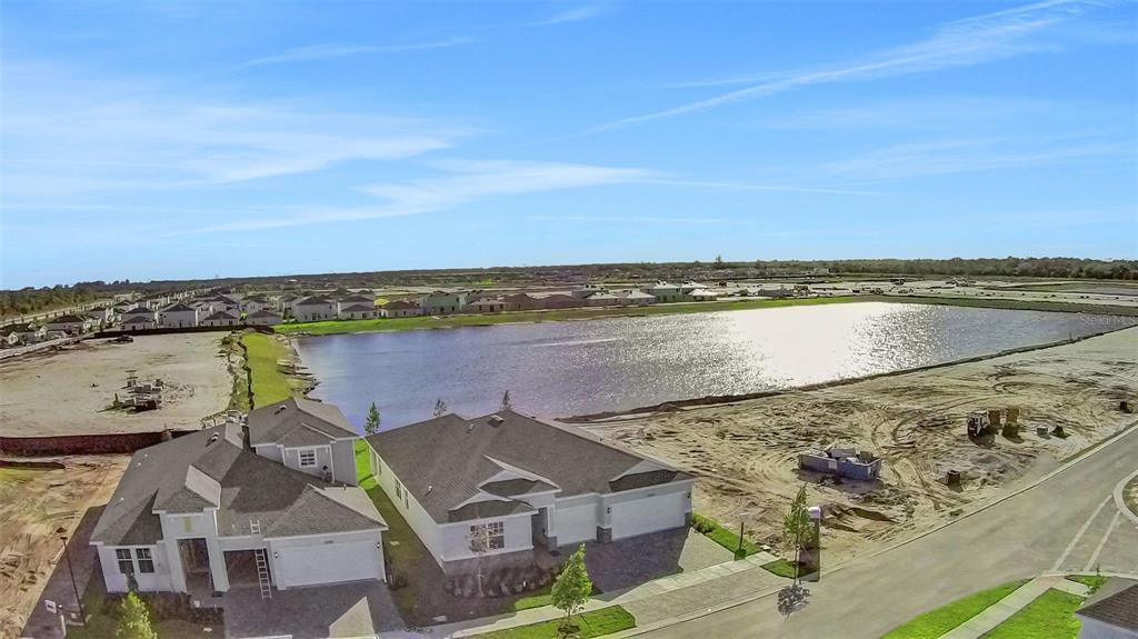 An aerial view shows two new houses situated next to a large retention pond — 10725 NW SUNCREST LOOP, PORT ST LUCIE, FL