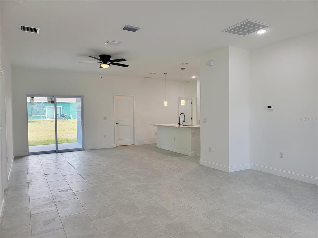 A modern kitchen features white cabinetry, a central island with a sink, and stainless appliances — 415 TONKLIN ROAD SW, PALM BAY, FL