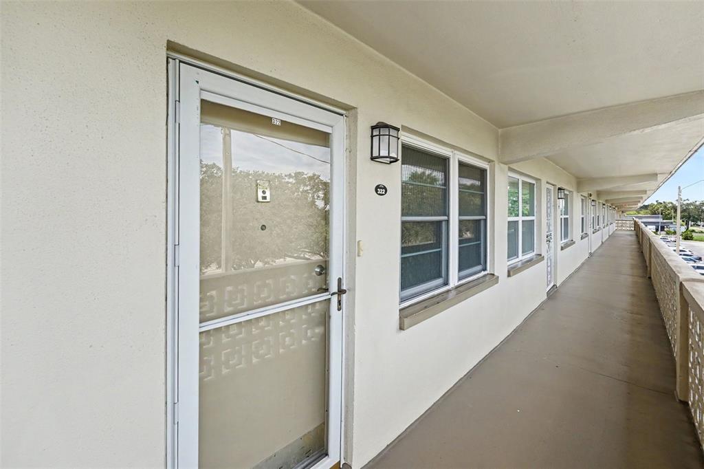 An exterior walkway leads to the entrance of a residential unit with a screen door — 951 79TH AVENUE N APT 322, ST PETERSBURG, FL