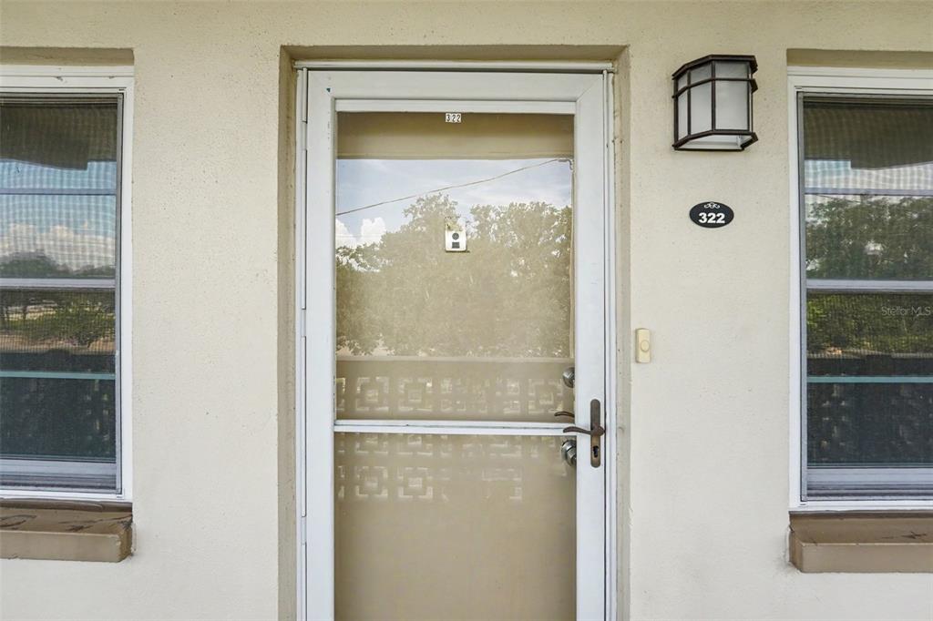 A white exterior door with a storm door and the number 322 sits between two windows — 951 79TH AVENUE N APT 322, ST PETERSBURG, FL