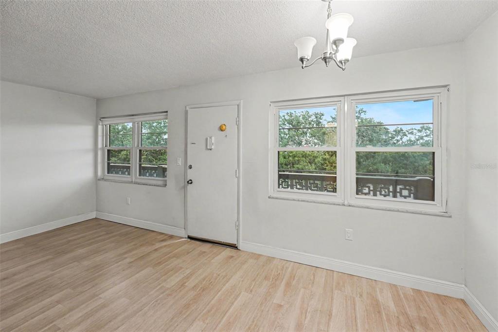 A room with light wood-look flooring, white walls, a central door, and two windows — 951 79TH AVENUE N APT 322, ST PETERSBURG, FL