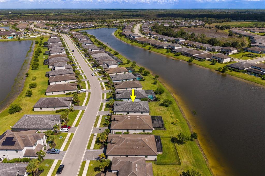An aerial view shows a residential street with houses bordering a large lake — 13845 PINE LODGE LANE, FORT MYERS, FL