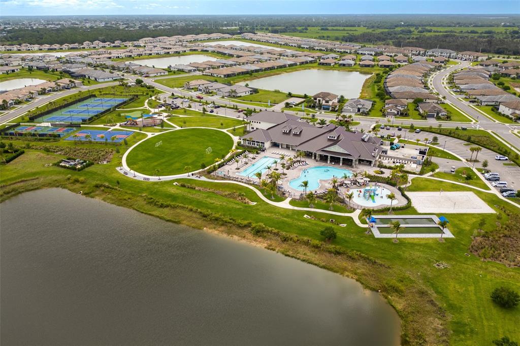 An aerial view shows a community clubhouse with a pool, sports courts, and surrounding lakes — 13845 PINE LODGE LANE, FORT MYERS, FL