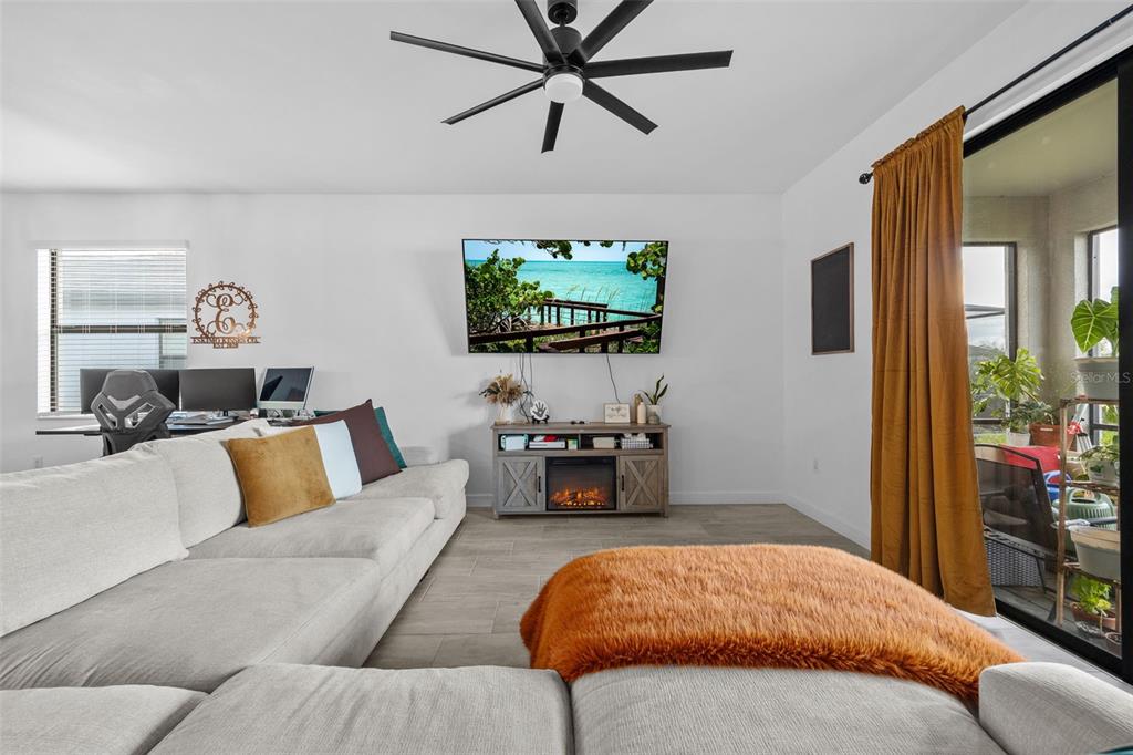 A living room features a sectional sofa, a fireplace media console, and a ceiling fan — 13845 PINE LODGE LANE, FORT MYERS, FL
