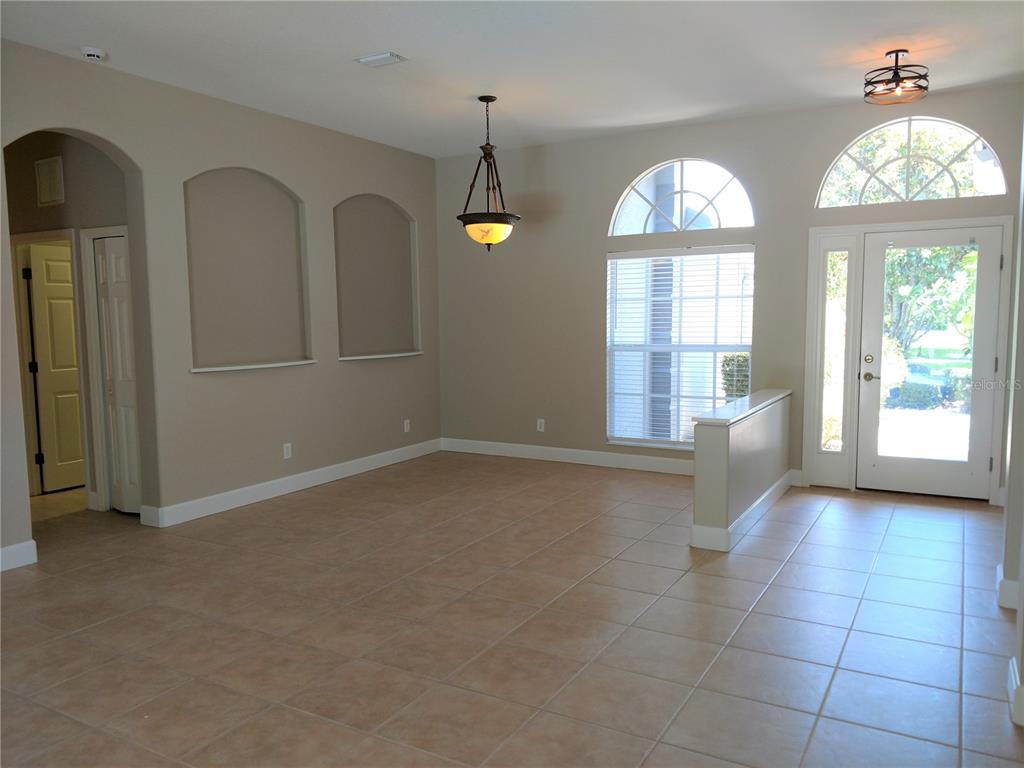 An empty room with tile floors, arched wall niches, a chandelier, and a front entrance — 919 SCHERER WAY, OSPREY, FL
