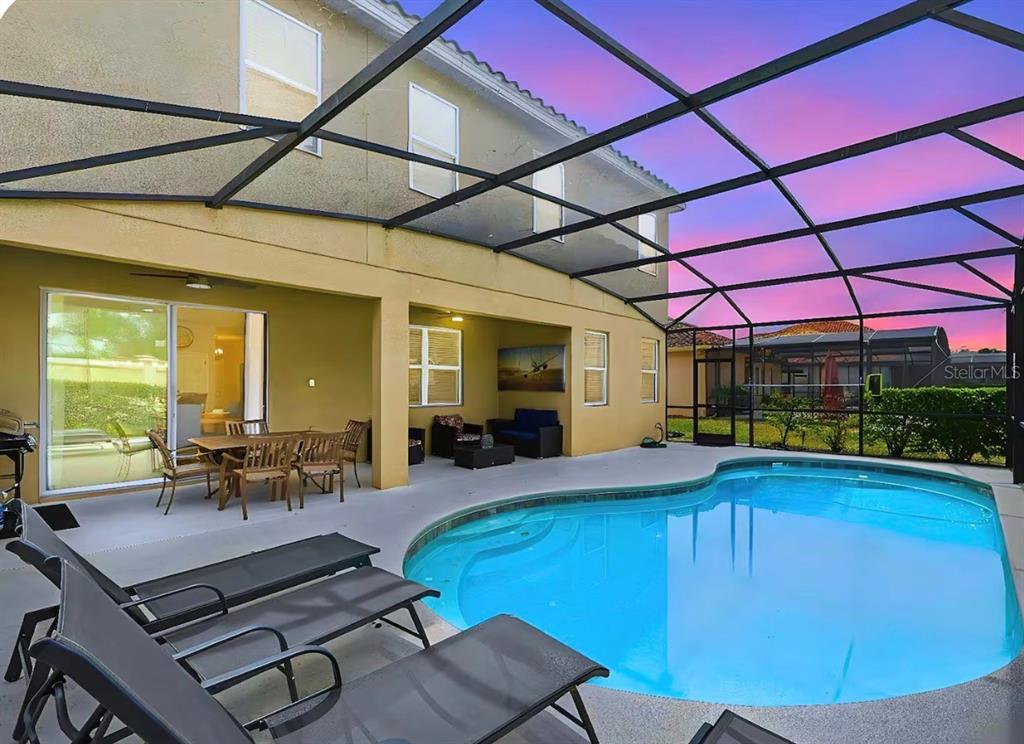 A screened-in patio features a swimming pool, outdoor dining furniture, and lounge chairs — 4035 OAKRISE LOOP, DAVENPORT, FL
