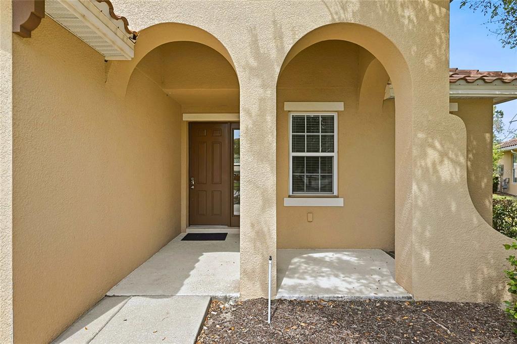 The exterior of a house features a covered entryway with two arched openings and stucco — 4035 OAKRISE LOOP, DAVENPORT, FL