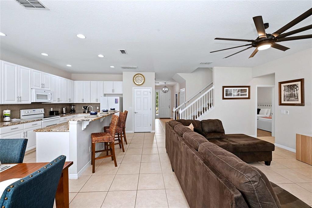 An open-concept kitchen with white cabinets and a breakfast bar overlooks a living area — 4035 OAKRISE LOOP, DAVENPORT, FL