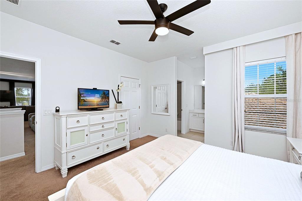 A bedroom features a white dresser, a ceiling fan, and an attached bathroom — 4035 OAKRISE LOOP, DAVENPORT, FL